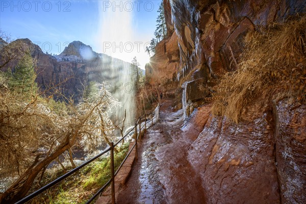 Waterfall falls from overhanging rock in winter