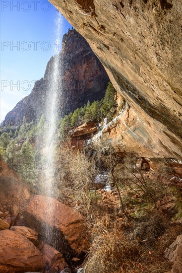 Waterfall falling from overhanging rock in winter