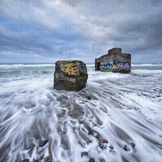 Old bunkers with graffiti in the surf of the Baltic Sea below the steep coast at stormy sea