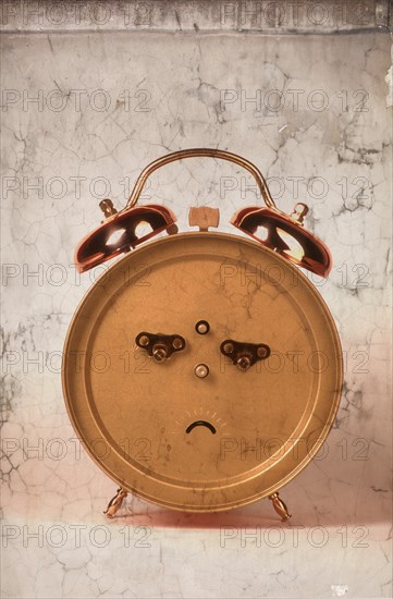 Back of an alarm clock in the shape of a frowning face