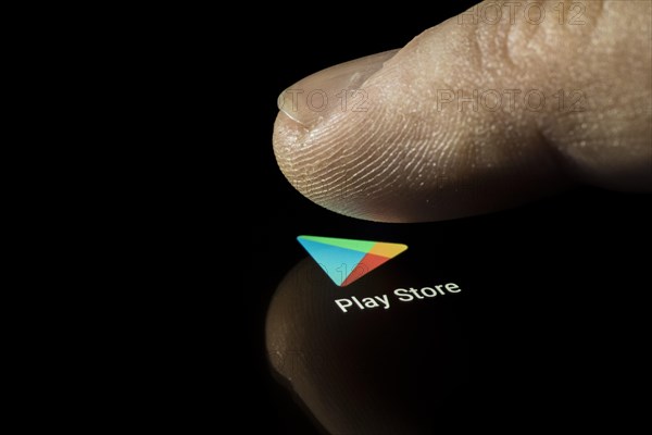 Play Store app icon on a display with finger