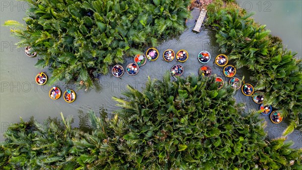 Tourists in Basket boats on river between palms at Coracle tour