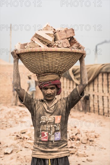 Brickyard worker carrying bricks in a basket on his head