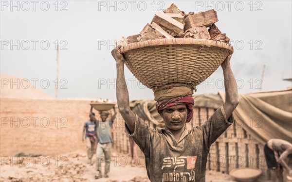 Brickyard worker carrying bricks in a basket on his head