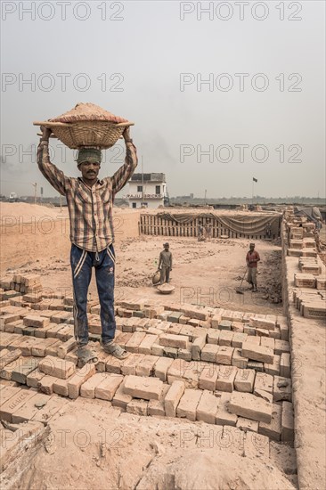 Brickyard worker carrying basket of ashes on his head