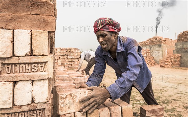 Brick factory worker stacks bricks