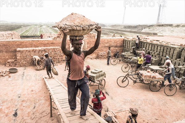 Brickyard worker carrying basket of ashes on his head