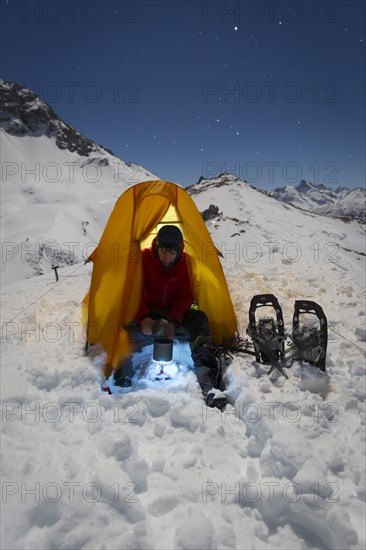 Snowshoe hikers melting snow for drinking water in the snow on the Madelejoch
