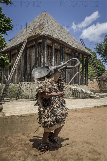 Dancer in traditional clothing wearing carved elephant mask