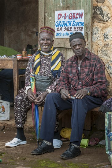 Two men sitting on bench at market