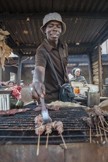 Seller grilling meat at street stand