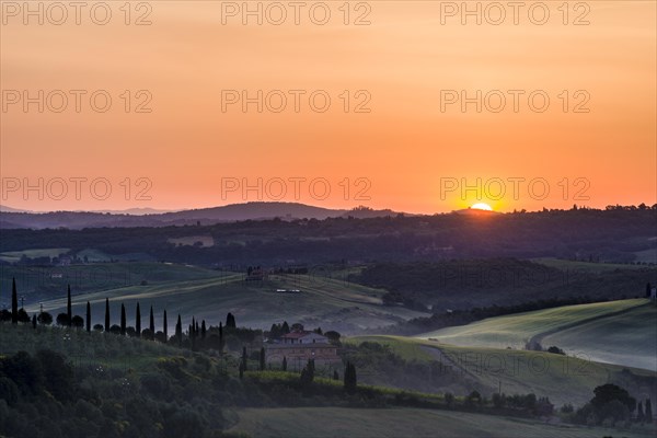 Typical green Tuscan landscape in Val d'Orcia with a farm on a hill