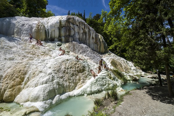 Accumulated white minerals and the pools of the hot springs of Bagni San Filippo in the middle of the forest