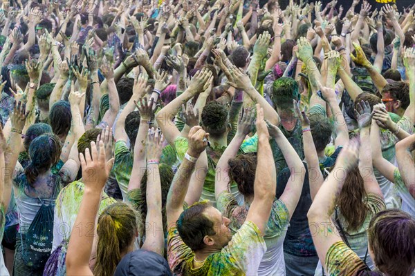 Thousands of young women and man are raising their arms at the colorful Holi festival