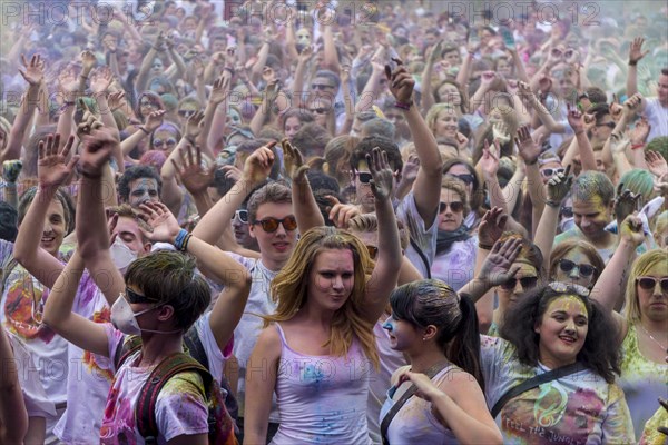 Thousands of young women and man are raising their arms at the colorful Holi festival