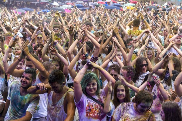 Thousands of young women and man are raising their arms at the colorful Holi festival