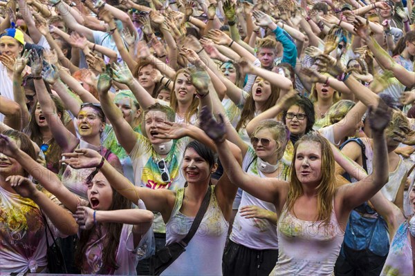 Thousands of young women and man are raising their arms at the colorful Holi festival