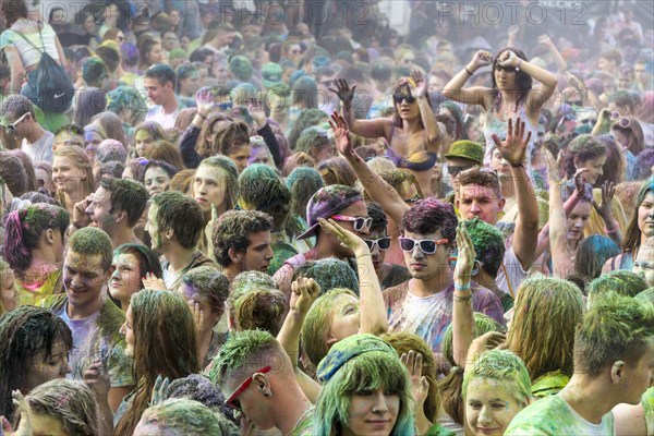 Thousands of young women and man are raising their arms at the colorful Holi festival