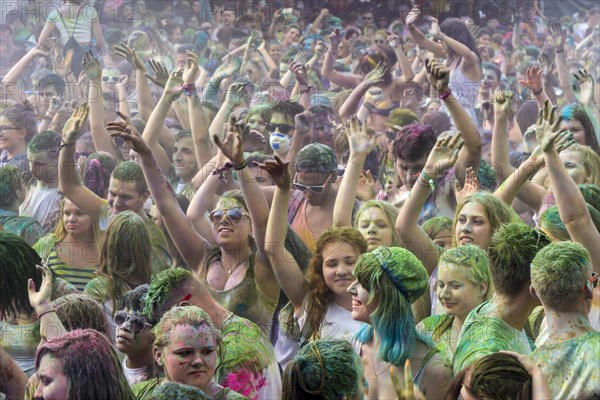 Thousands of young women and man are raising their arms at the colorful Holi festival