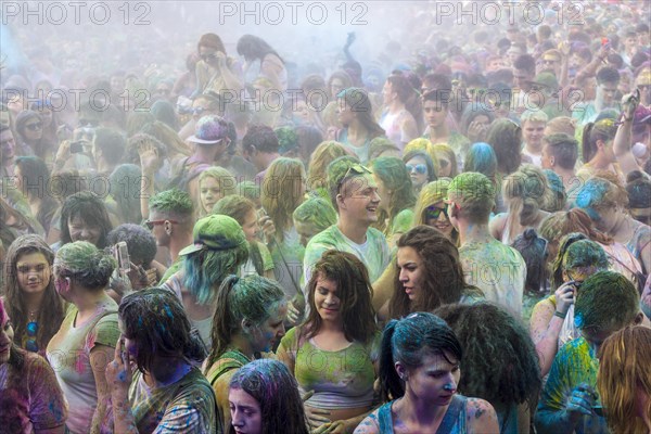 Thousands of young women and man are hardly visible because of color powder in the air at the colorful Holi festival