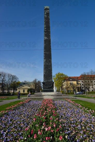 Obelisk with flower bed in front of houses roundabout