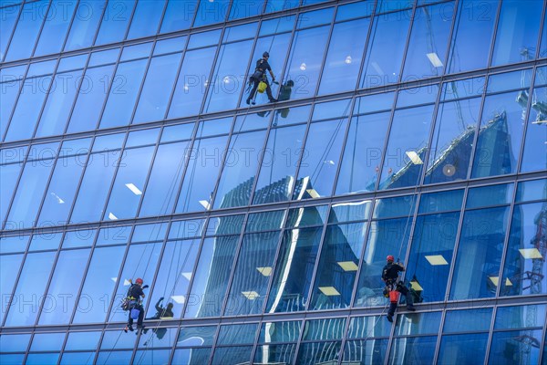 Window cleaner on glass facade of a high-rise building