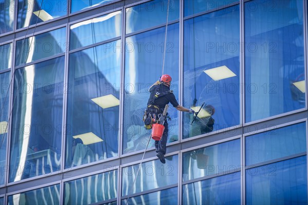 Window cleaner on glass facade of a high-rise building