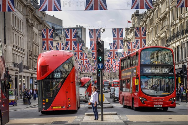 Double-decker buses in street with many British flags