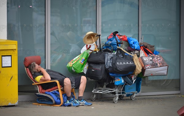 Homeless person with many bags on luggage trolley