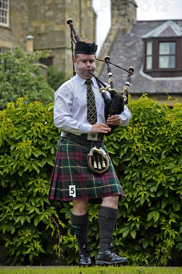 Solo bagpiper playing bagpipes in kilt