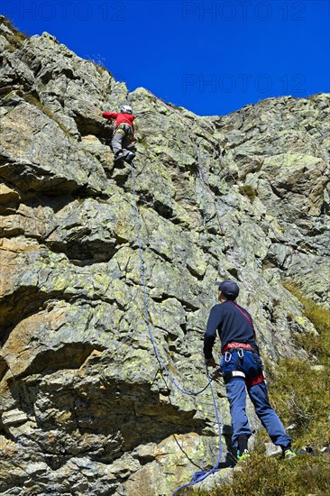 Man belaying child on rock face