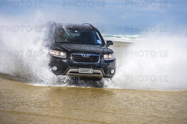 Black Hyundai Santa Fe 4x4 SUV drives on the beach of Ninety Mile Beach in the water