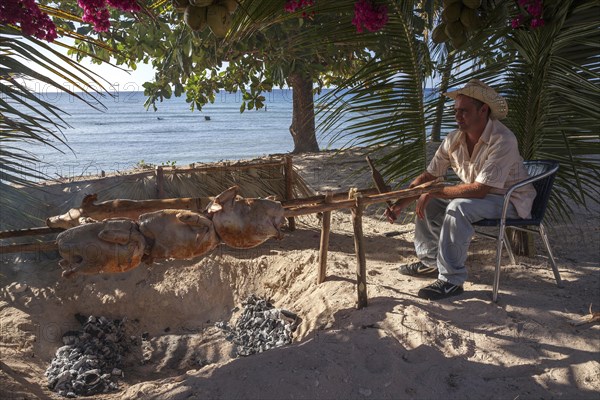 Cuban man grilling turkeys and suckling pig at the beach of Playa Ancon