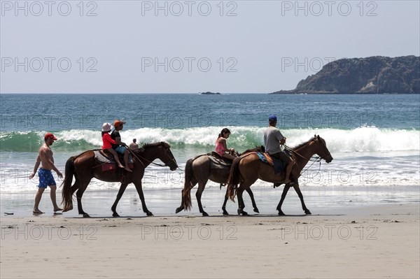 Riders on horseback on the beach Playa Espadilla