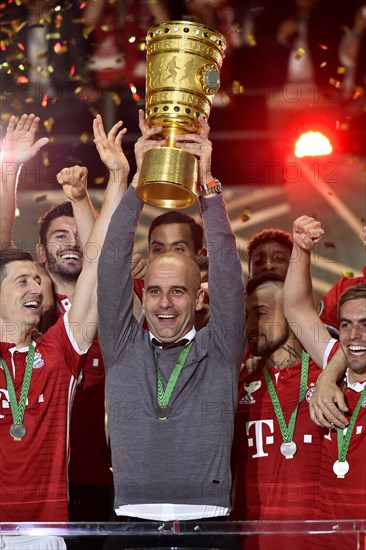 Coach Josep Pep Guardiola lifting the DFB Cup in the air