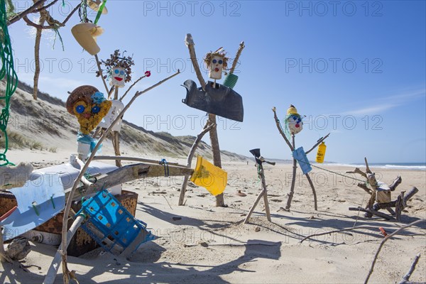 Figures from washed up plastic garbage and flotsam on the sandy beach