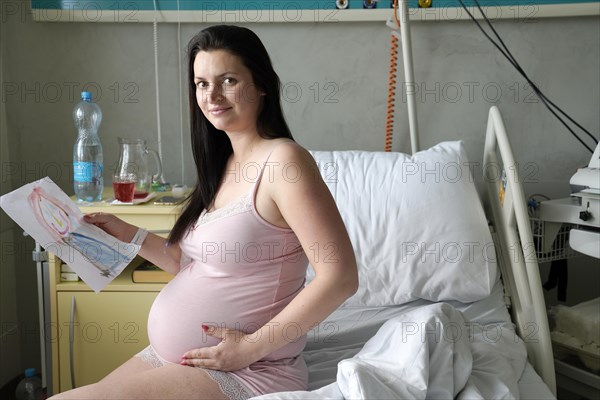 Pregnant woman sitting on sickbed in sickroom