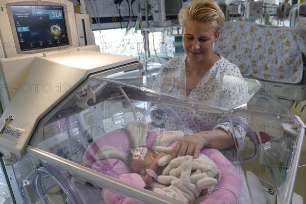 Mother of twins with one of her newborns in an incubator