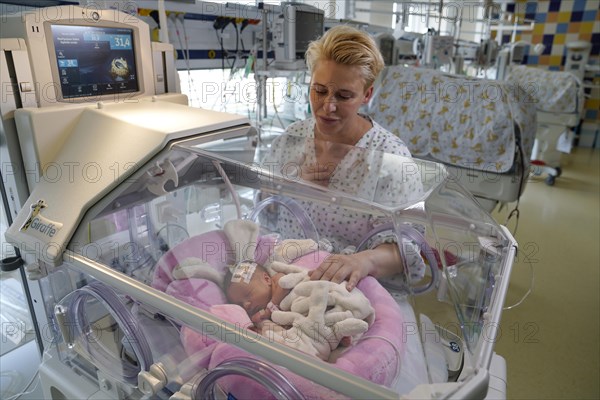 Mother of twins with one of her newborns in an incubator