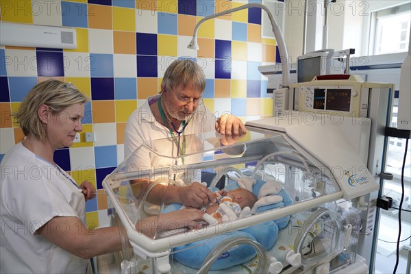 Doctor and nurse examining a newborn in an incubator