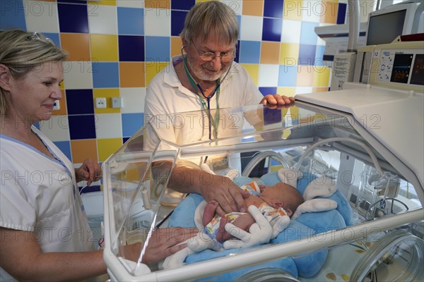 Doctor and nurse examining a newborn in an incubator