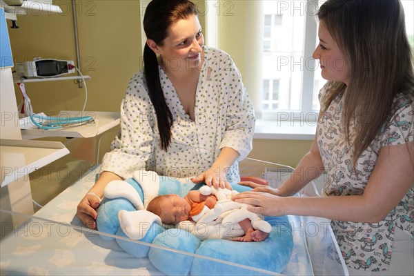 Mother with nurse takes care of newborn in intensive care unit