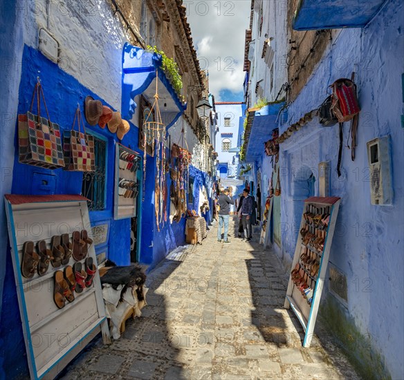 Sale of leather sandals in narrow lane with blue houses