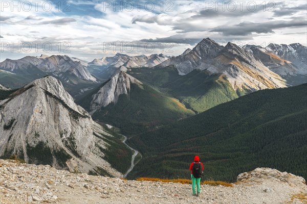 Female hiker views from summit over mountain landscape