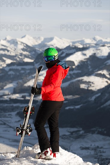 Female skier with ski helmet standing with ski at the ski slope above the valley