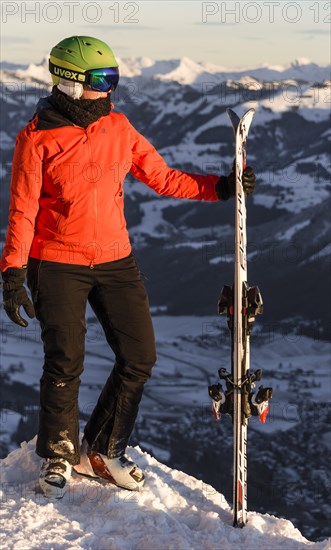 Female skier with ski helmet standing with ski at the ski slope above the valley