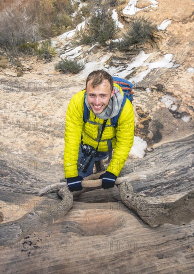 Young smiling hiker climbs wooden ladder