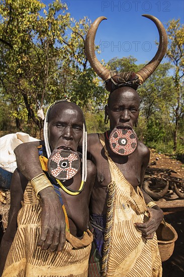 Two women with large lip plates and horns as headdress