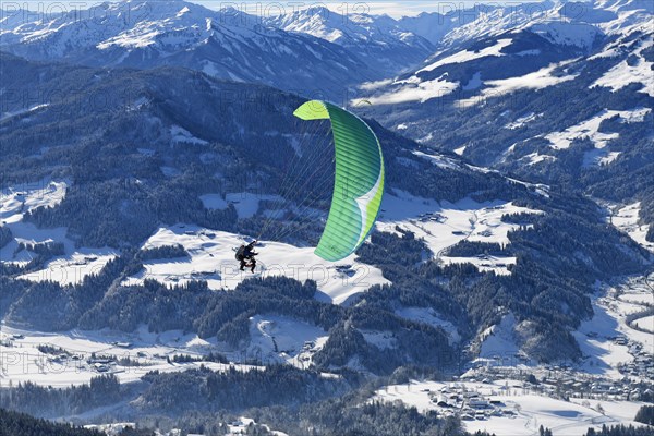 Paraglider flies from the Hohe Salve into the valley of Hopfgarten