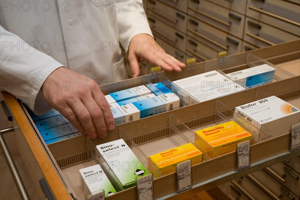 Apotheker taking medication from cabinet in a pharmacy